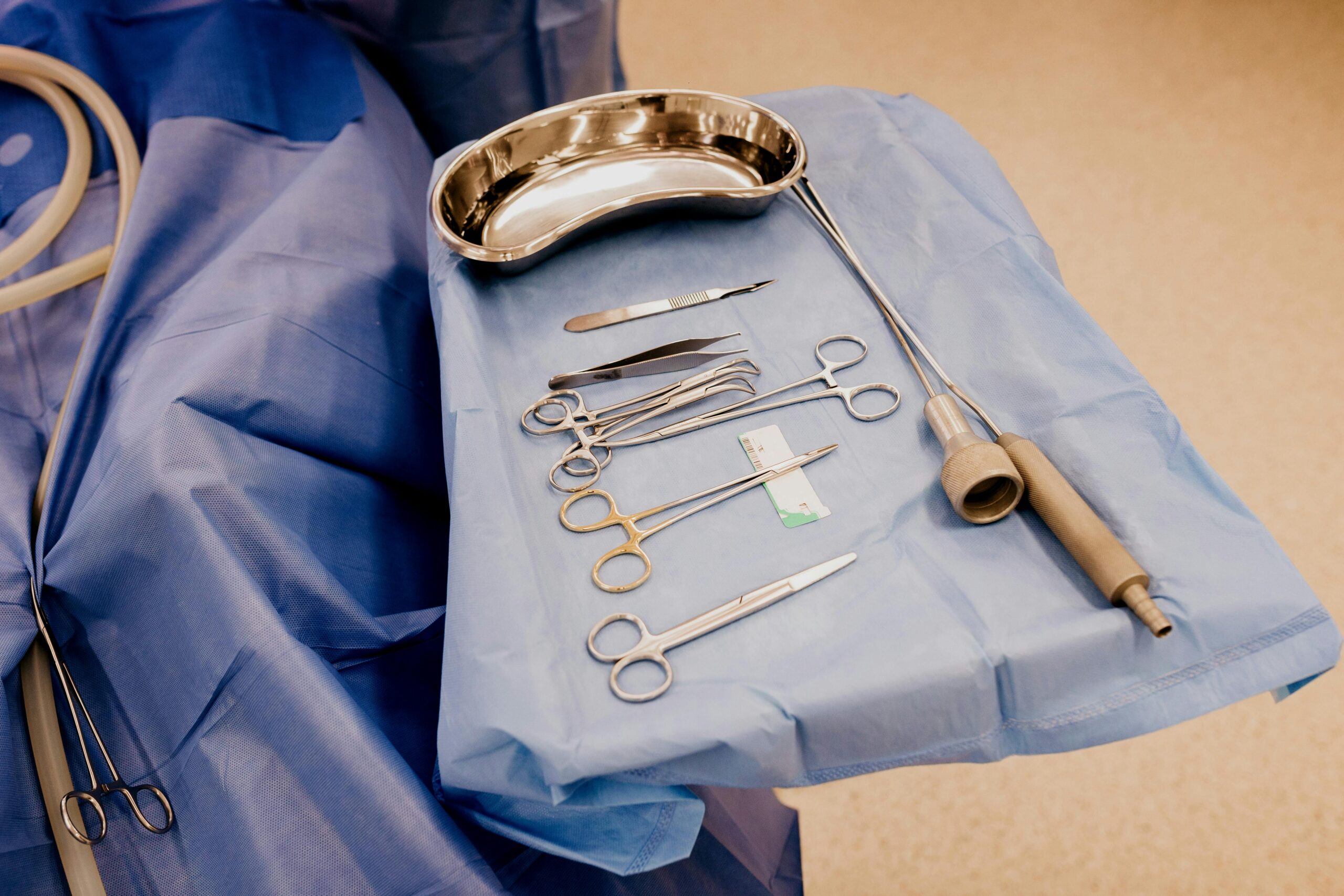 A set of surgical instruments arranged on a blue drape in a sterile operating room setting.